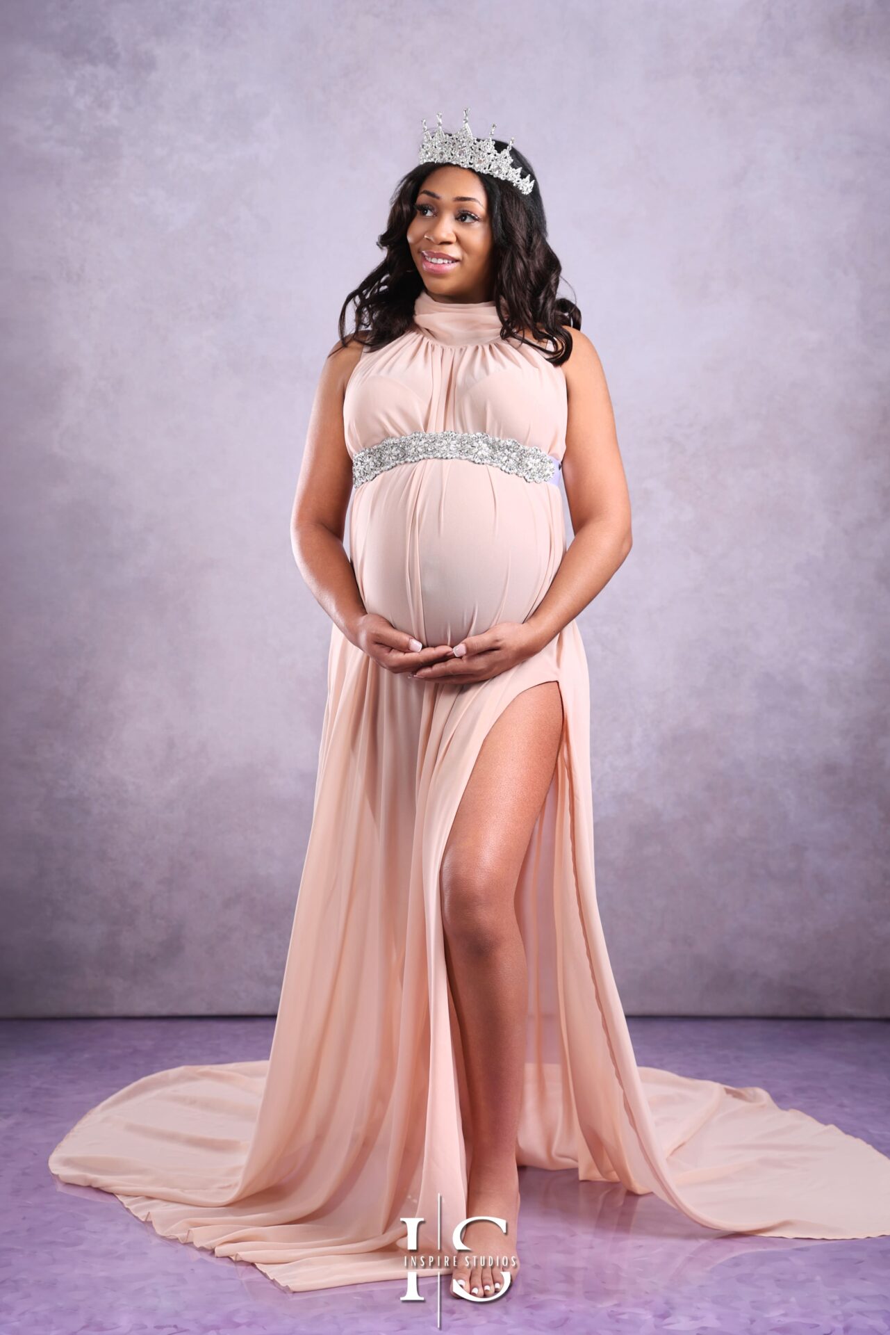Studio maternity photoshoot with a glowing mother-to-be wearing a soft pink dress.