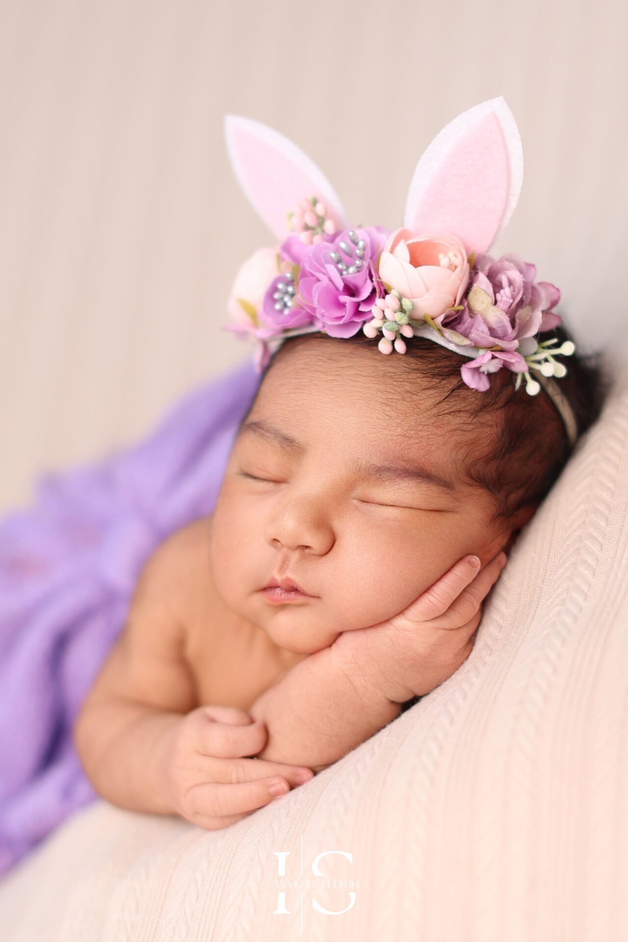 Studio photo of a newborn girl peacefully sleeping in a floral setting.