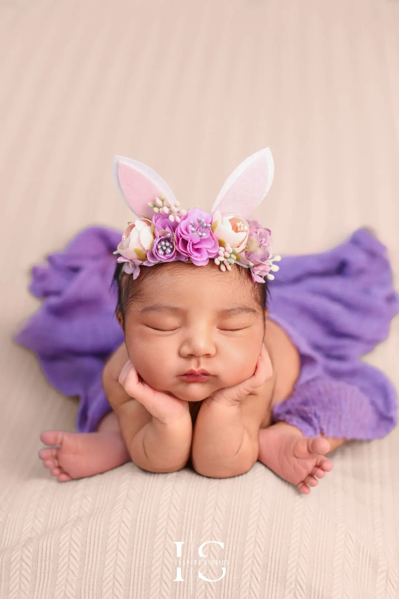 Peaceful newborn girl wrapped in pink during her studio photoshoot.