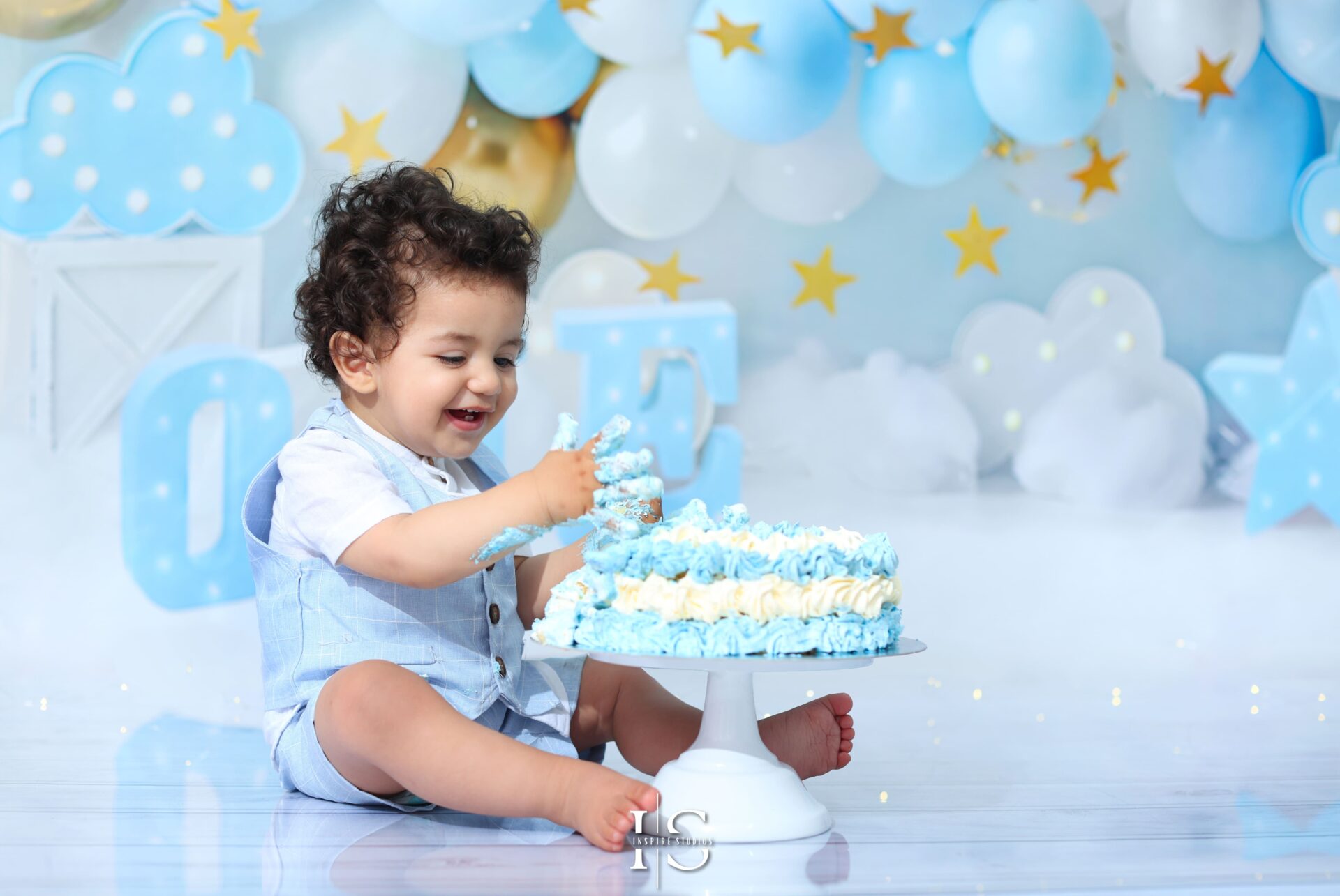 Baby boy enjoying a smash-the-cake photoshoot in a studio setting