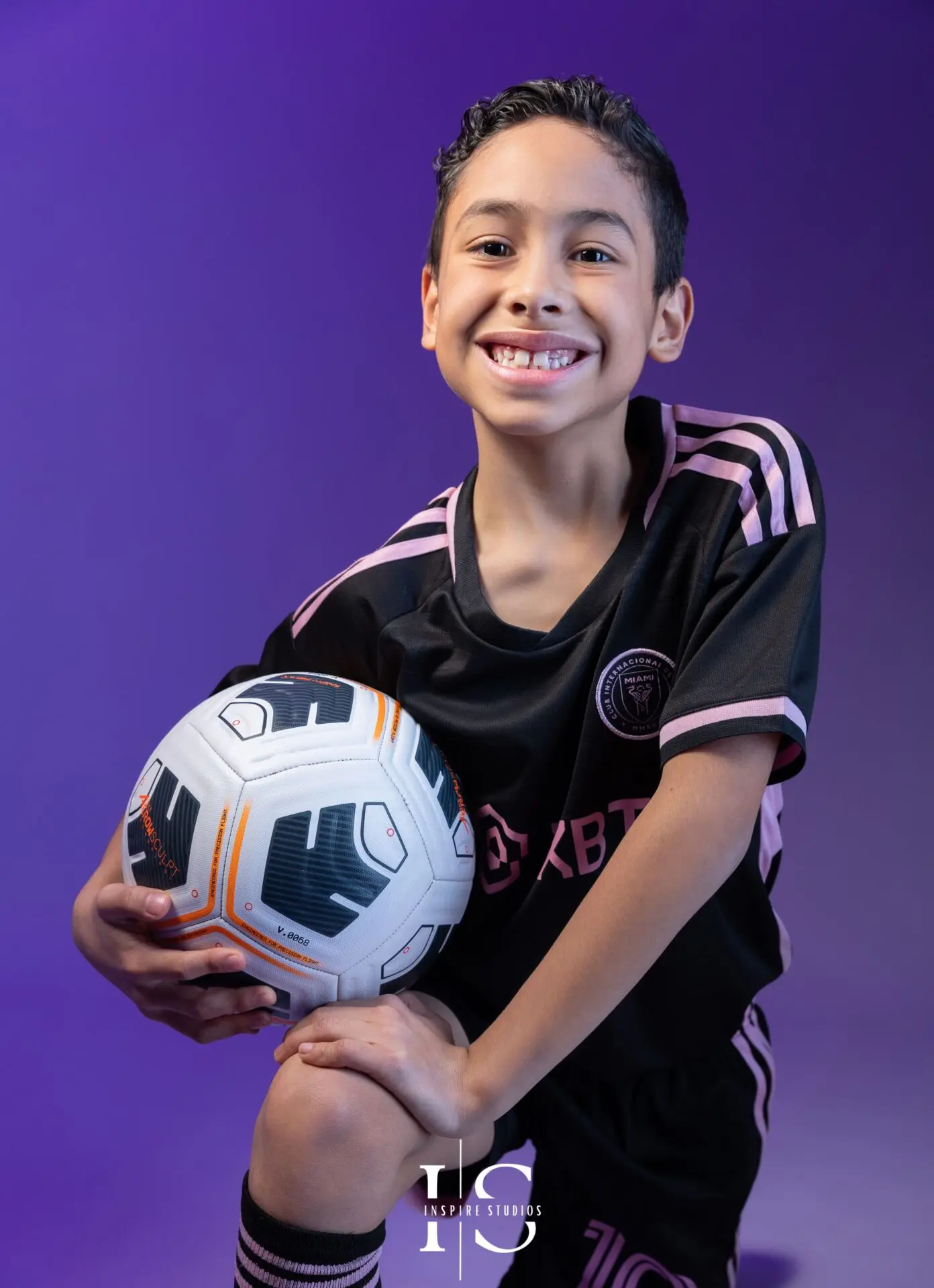 Child in sports-inspired studio photoshoot London with football props