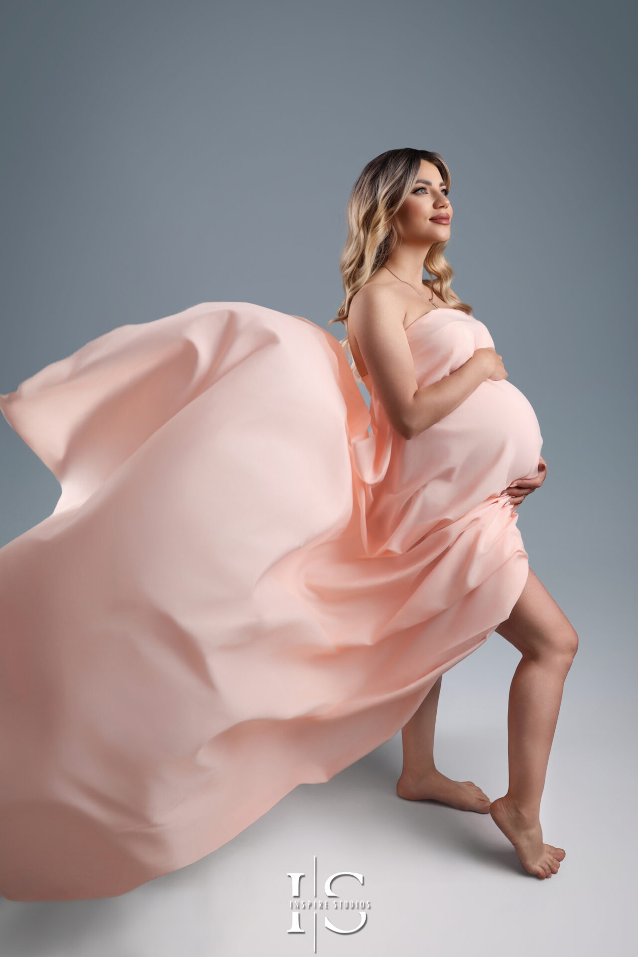 Pregnant woman in studio maternity photoshoot with flowing fabric in London.