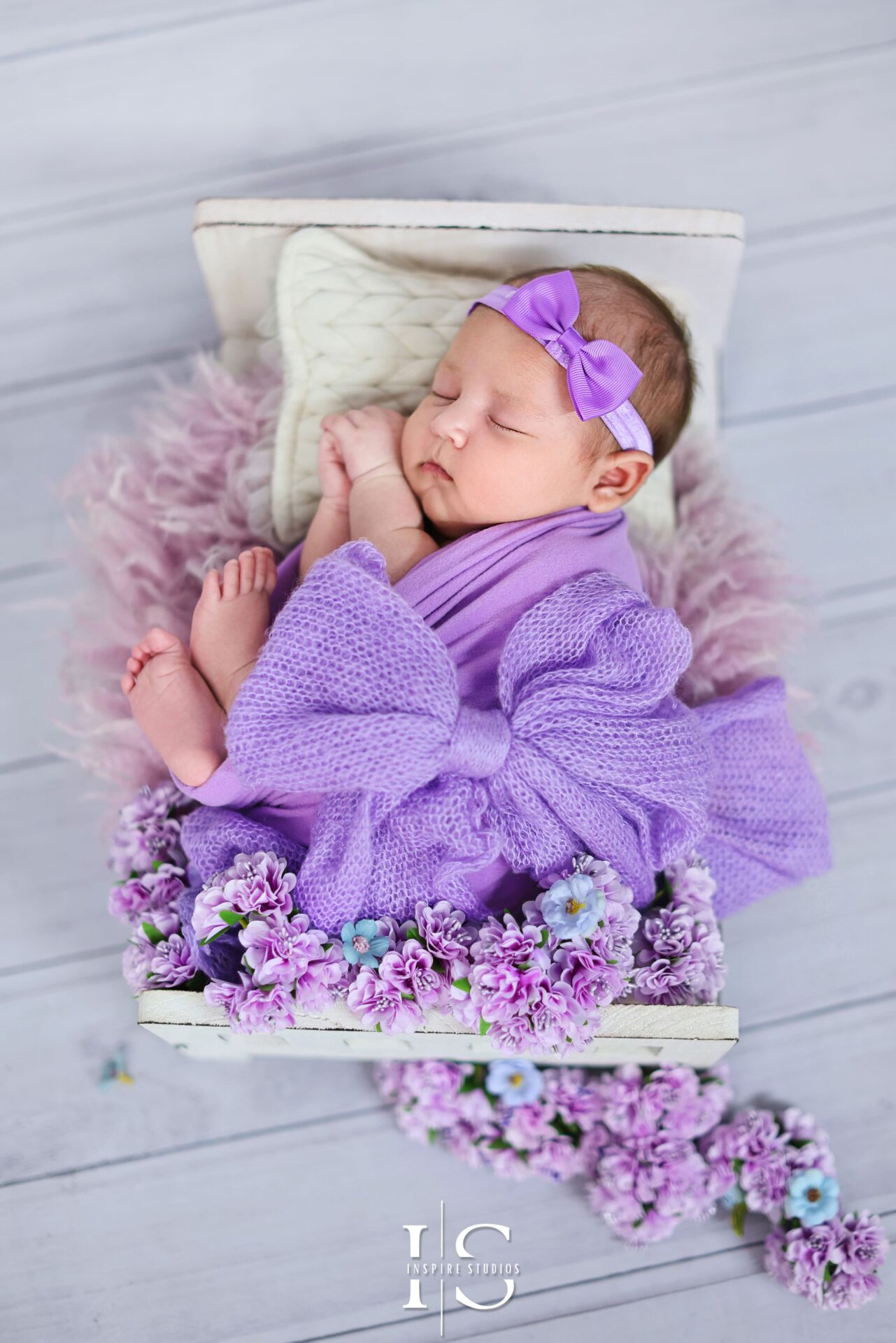 Newborn baby girl studio photography in East London, featuring a sleeping infant in a soft pink wrap and cozy setup