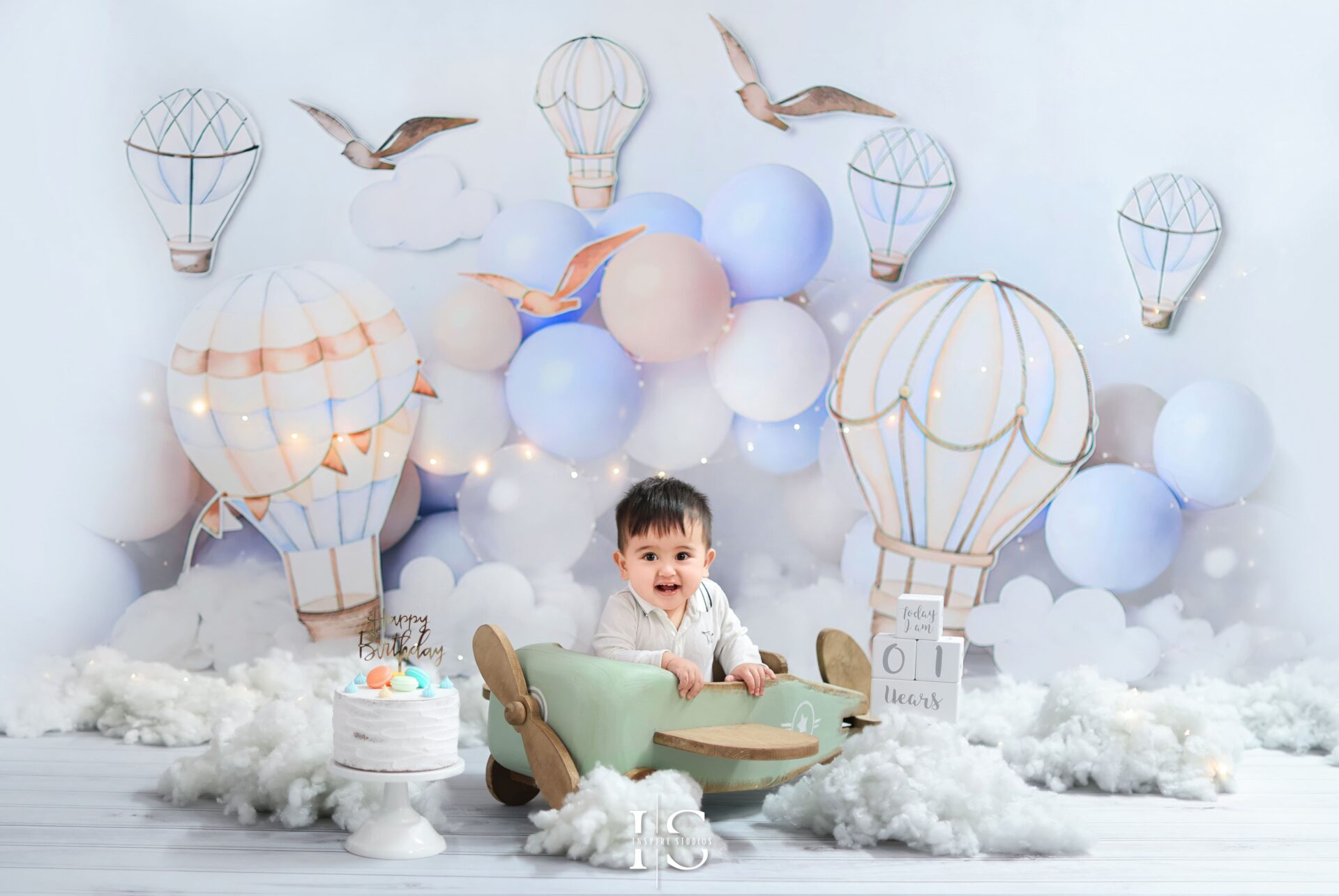 One-year-old celebrating first birthday with explorer-themed studio photoshoot featuring playful props and adventurous setup