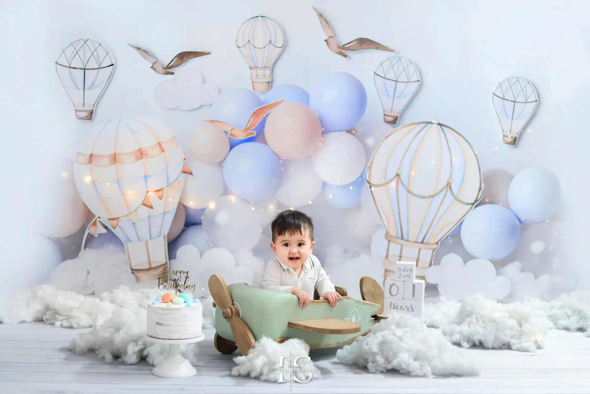 One-year-old celebrating first birthday with explorer-themed studio photoshoot featuring playful props and adventurous setup