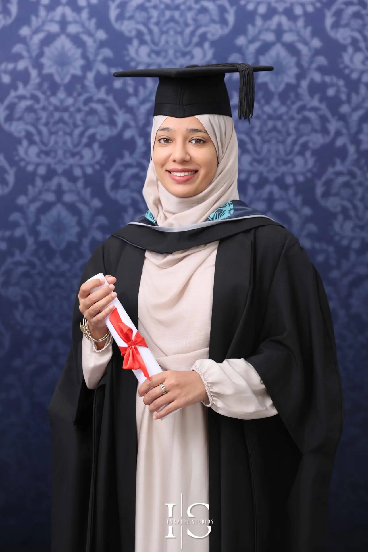 Graduate posing for a professional studio portrait in London wearing a cap and gown.