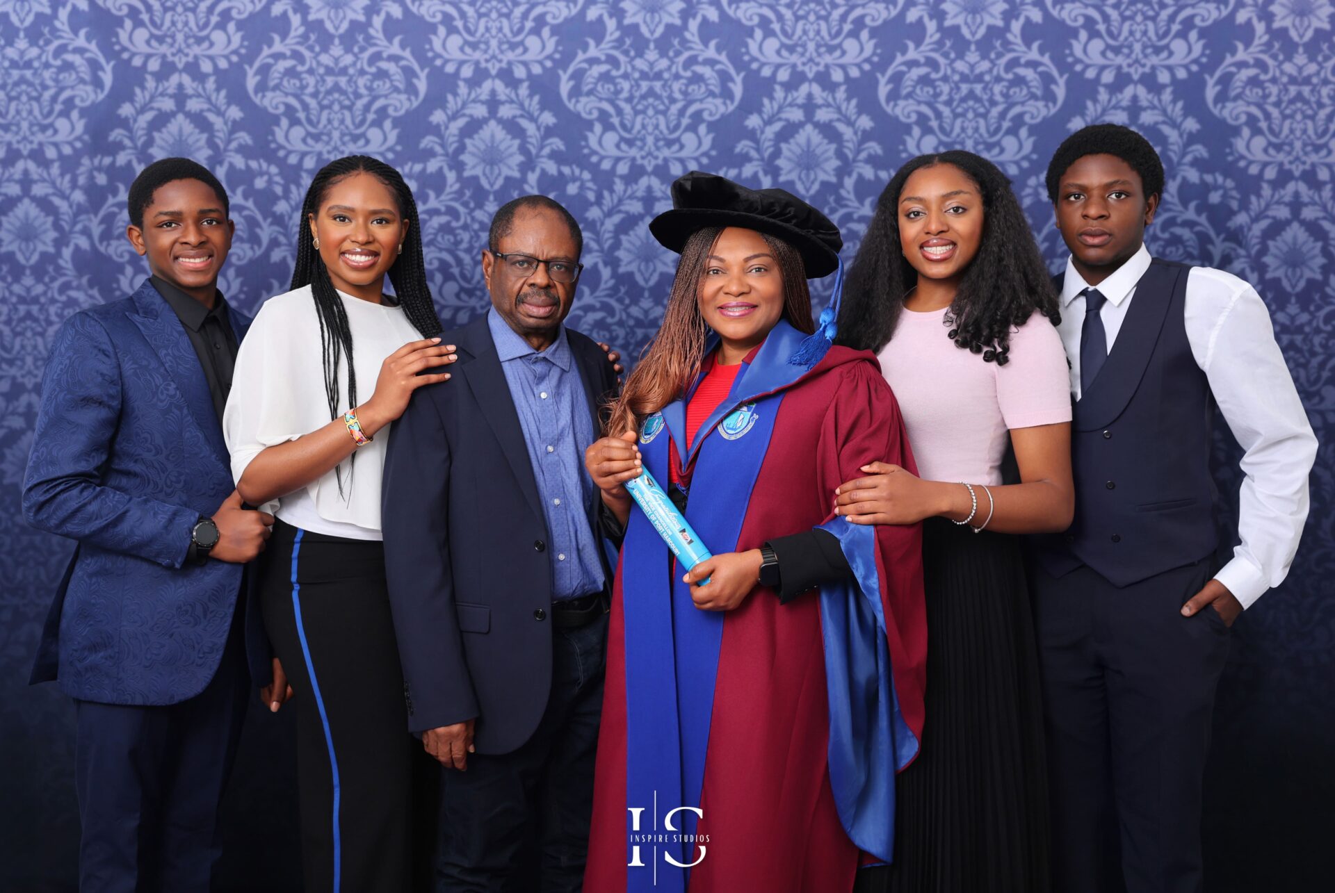 Graduate celebrating with family during a professional studio photoshoot with joyful poses and formal attire