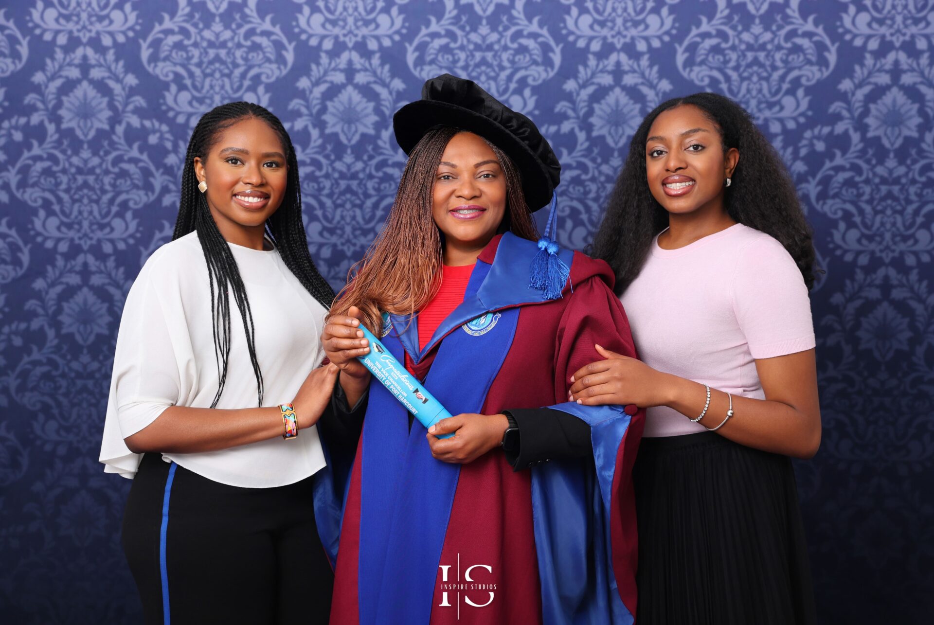 University graduate posing with family for a professional studio portrait celebrating academic success