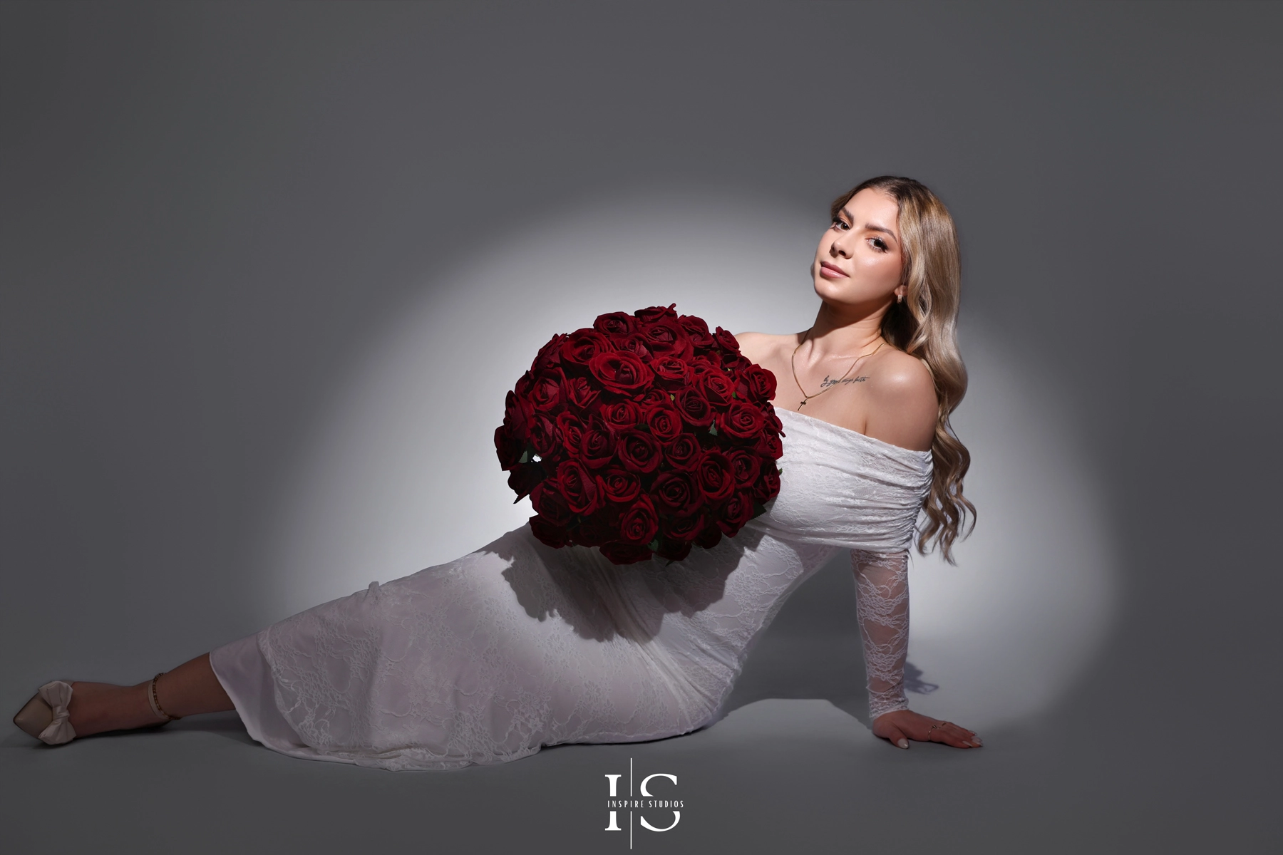 Studio-inspired 20th birthday photoshoot with red décor, rose bouquet, heart balloons, and a striking red outfit, posed against a professional photography backdrop.