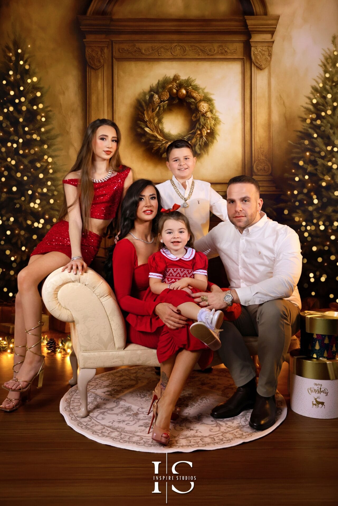 Smiling family with children posing for a festive Christmas photoshoot with holiday decorations and warm lights.