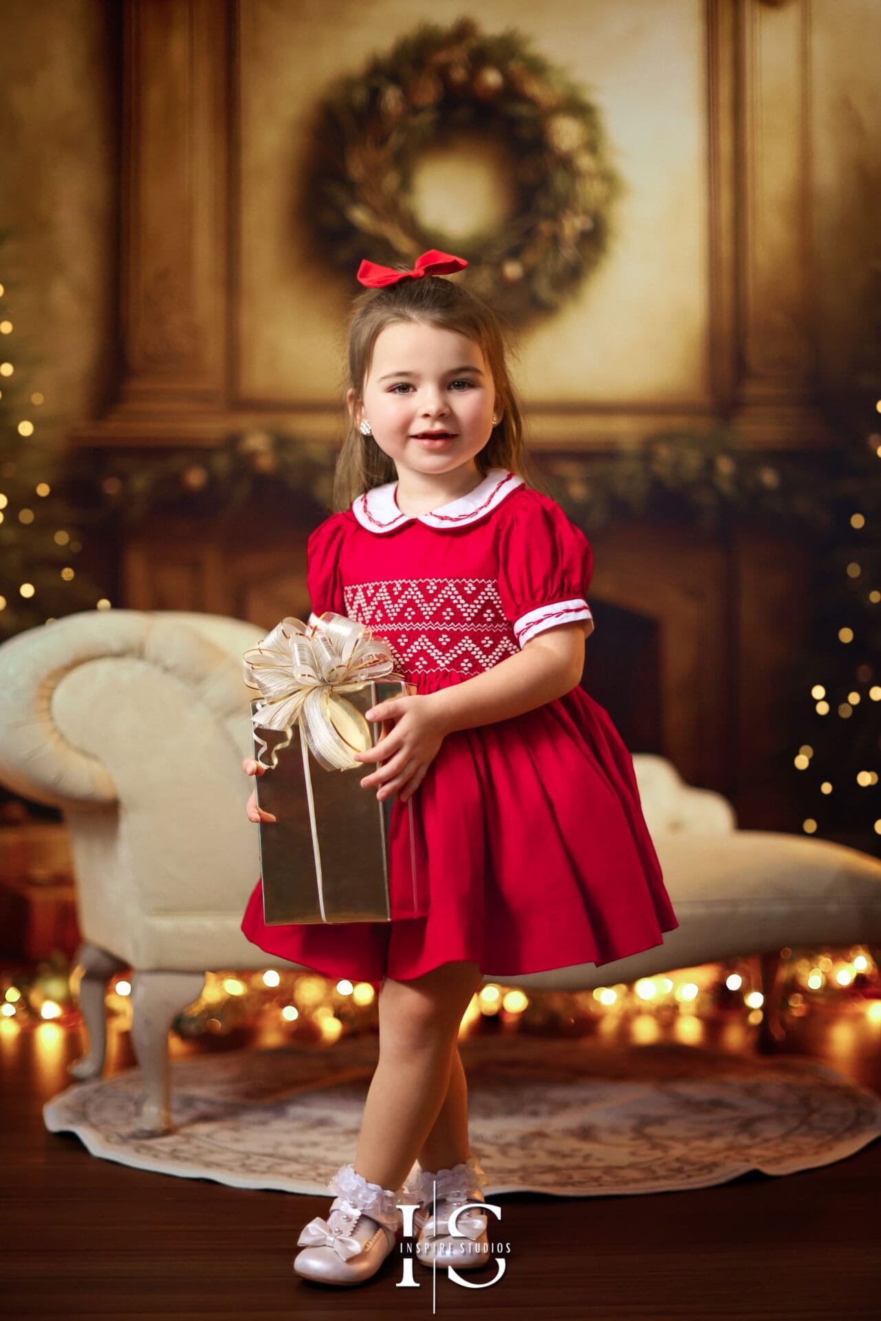 Young girl posing in a Christmas studio portrait with festive decorations and holiday-themed background.