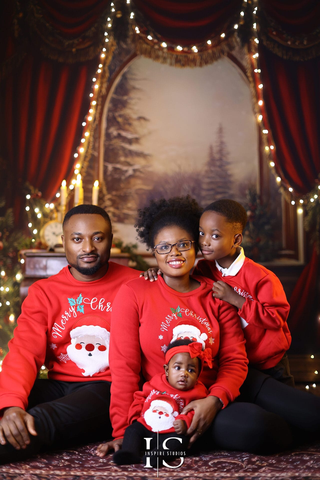 Smiling family photographed in a professional studio with Christmas decorations, festive props, and warm holiday lighting.