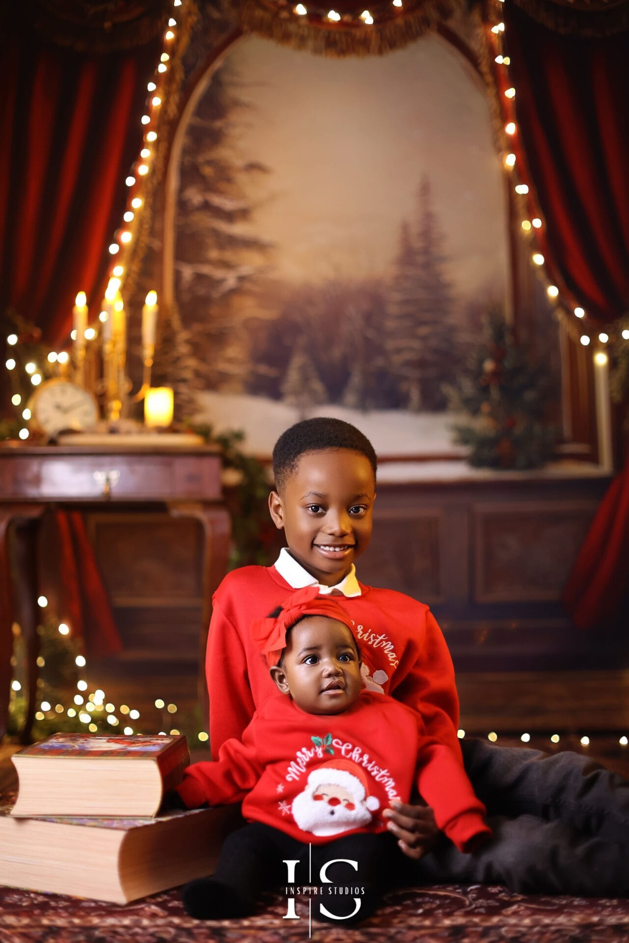 Smiling toddler sitting in a Christmas-themed studio setup with festive decorations and soft lighting.