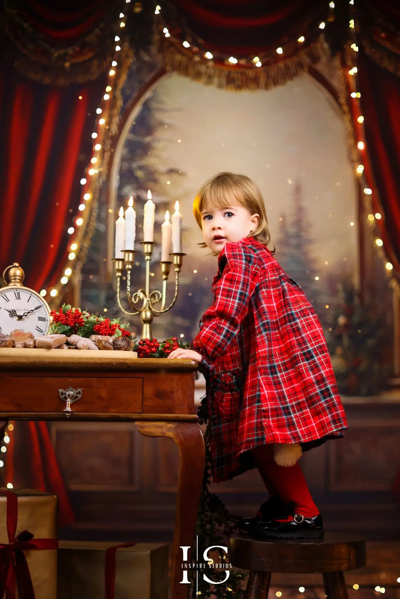 Cute toddler photographed in a festive Christmas studio with holiday props and bright seasonal décor.