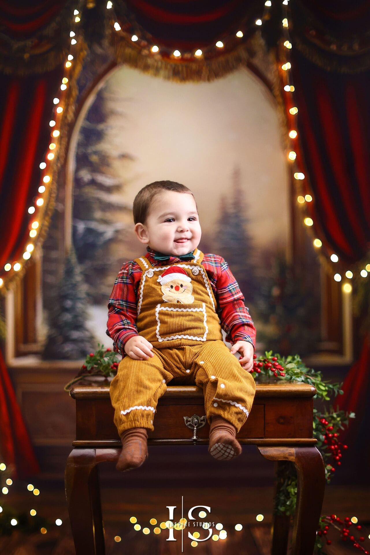 Toddler sitting in a Christmas-themed photography studio with festive décor and seasonal lighting.