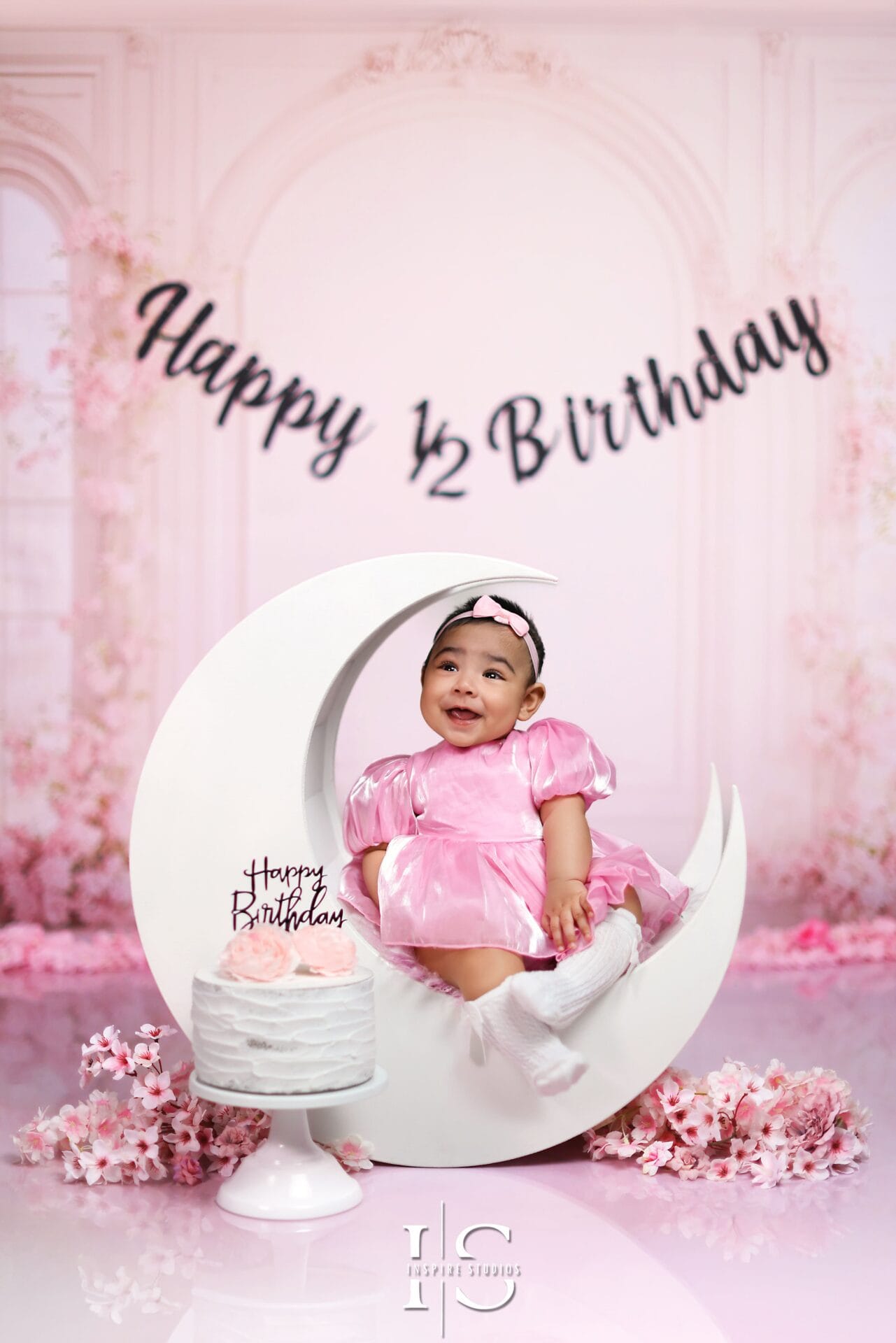 Six-month-old baby girl smiling during a milestone photoshoot with natural expressions and soft tones