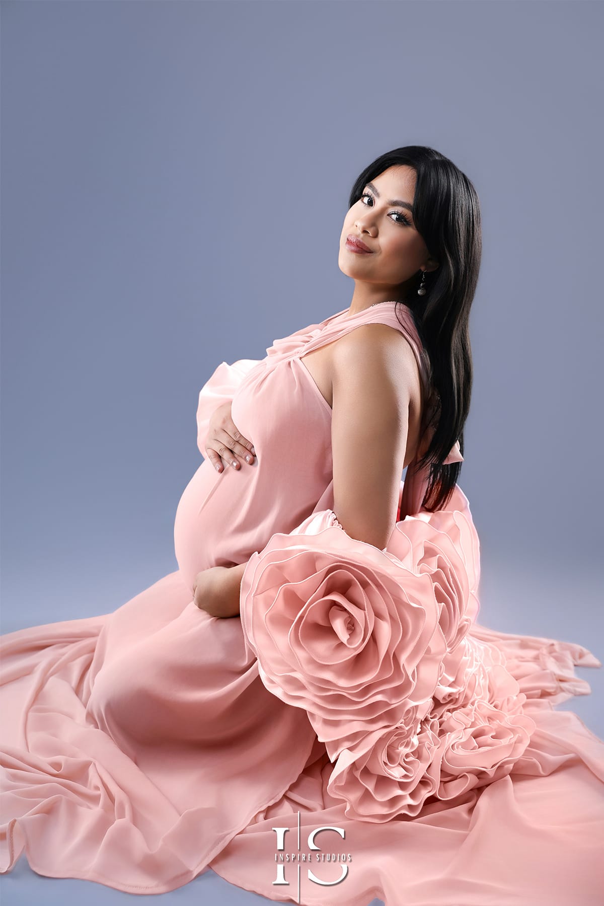 Pregnant woman wearing peach gown during maternity photoshoot in soft natural light