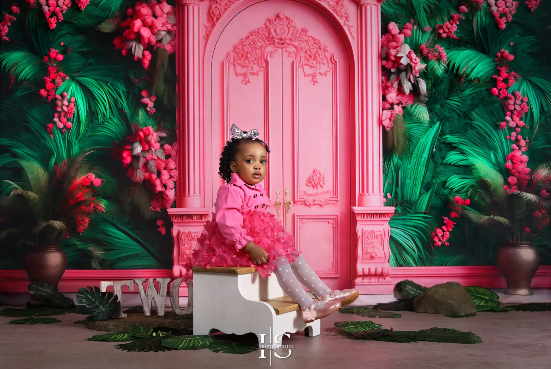 Two-year-old girl smiling during birthday photoshoot with pastel balloons and number 2 decoration
