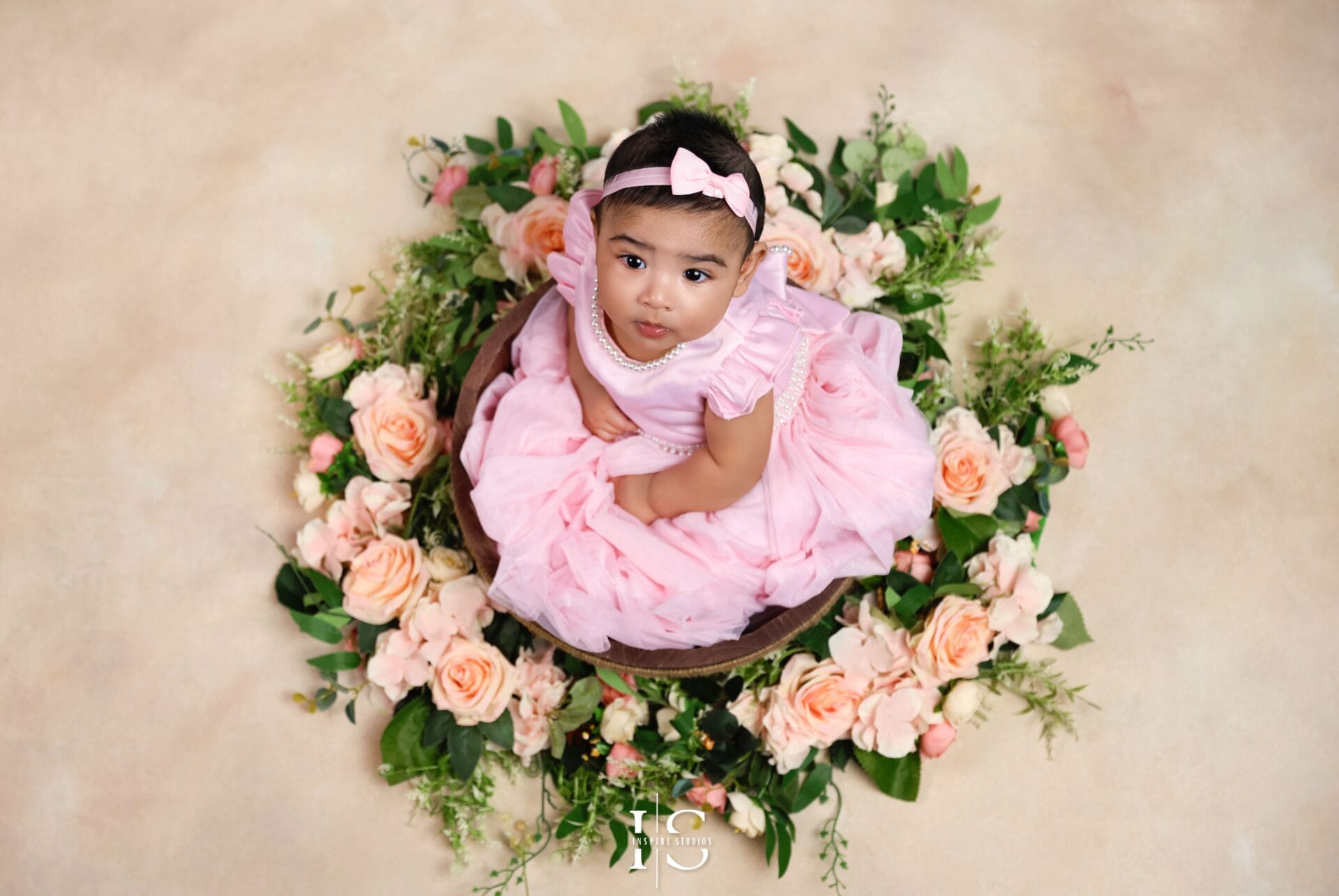 6-month-old baby girl sitting on a soft blanket during a professional children photoshoot, smiling at the camera in natural light
