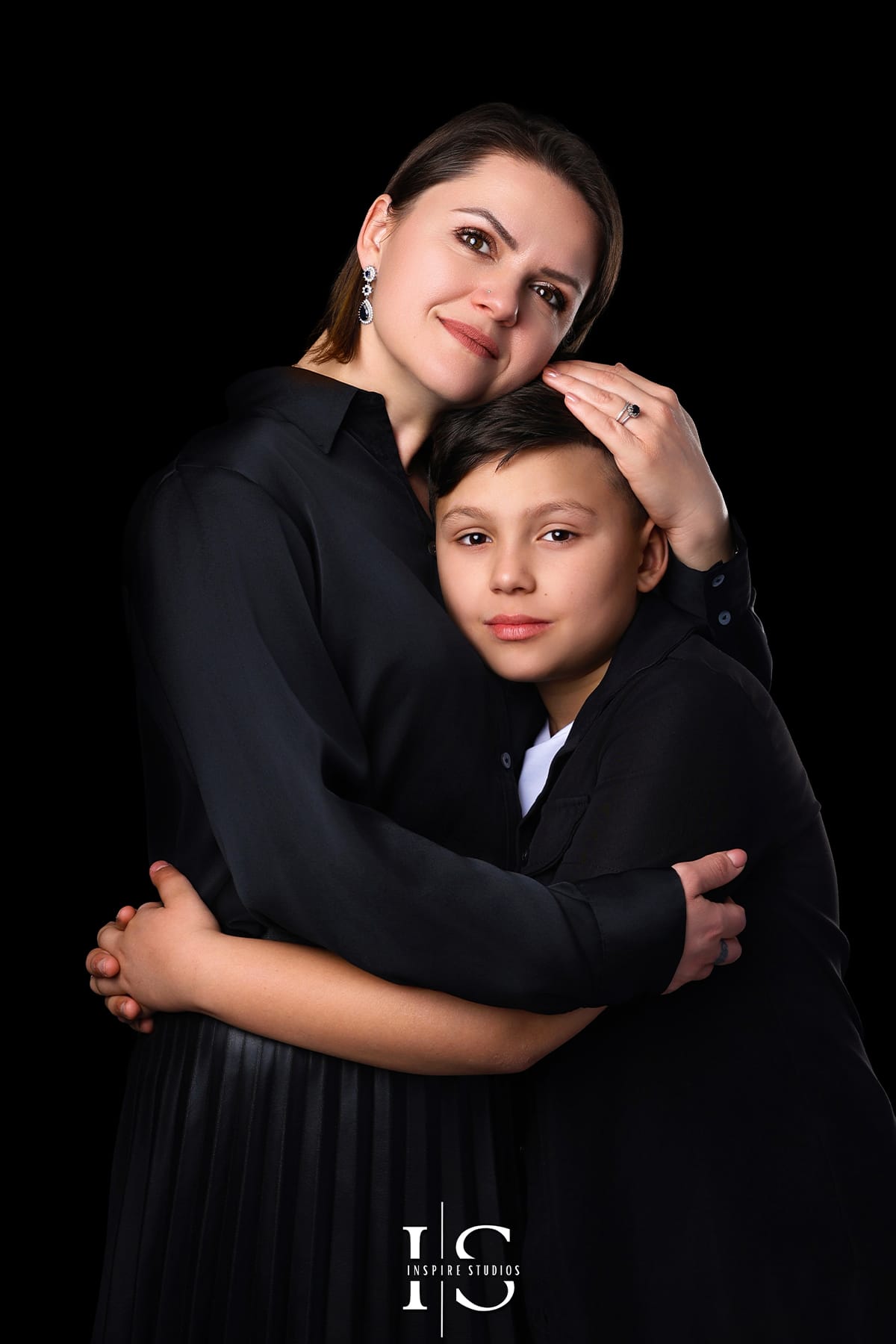 Mother and son fine art portrait during a professional studio photoshoot in London, showing an elegant black background family portrait with soft studio lighting.