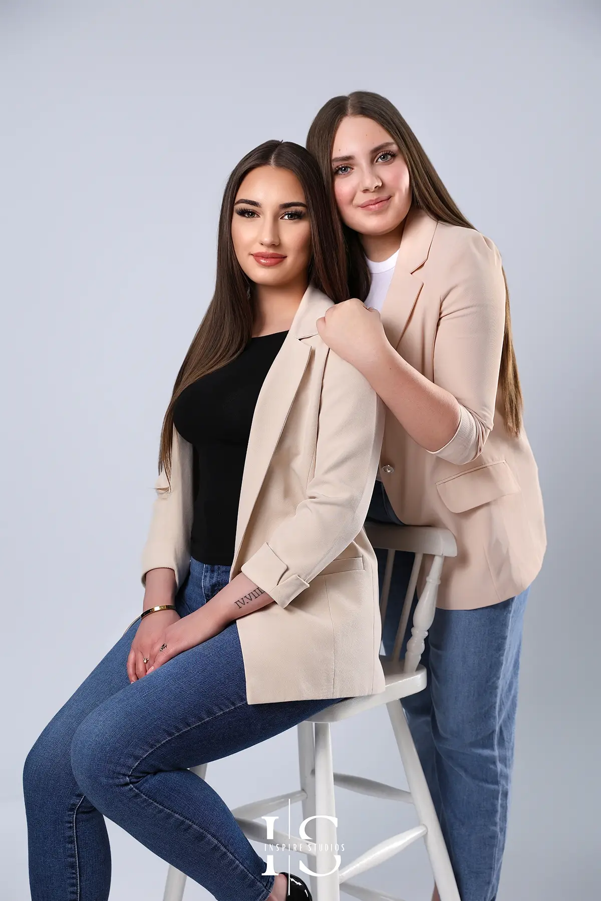 Two sisters hugging and smiling during a family studio photoshoot, showing love and connection