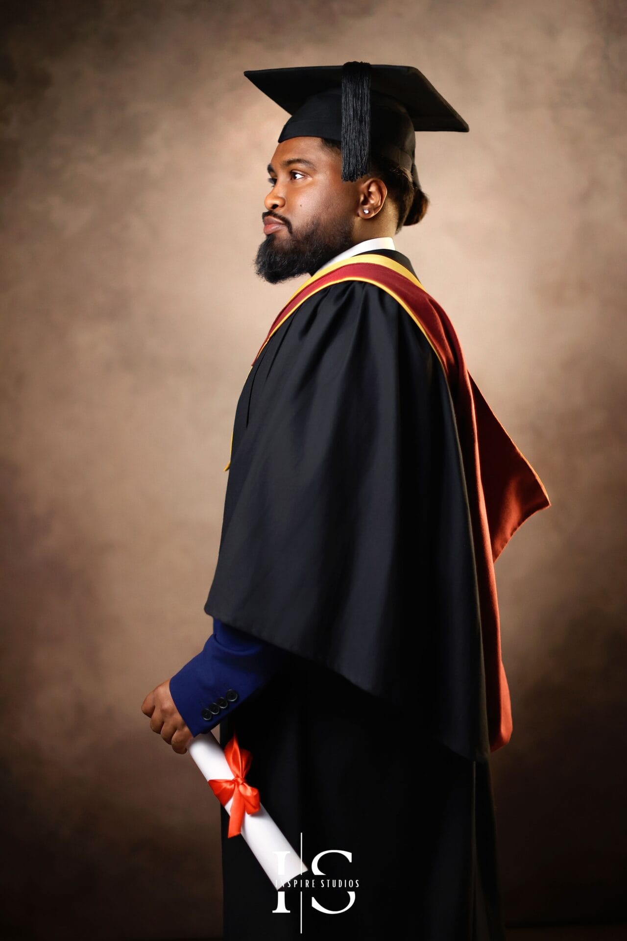 Graduate posing in a vintage-style studio portrait photoshoot in London with elegant classic backdrop, formal graduation gown and timeless fine art lighting.