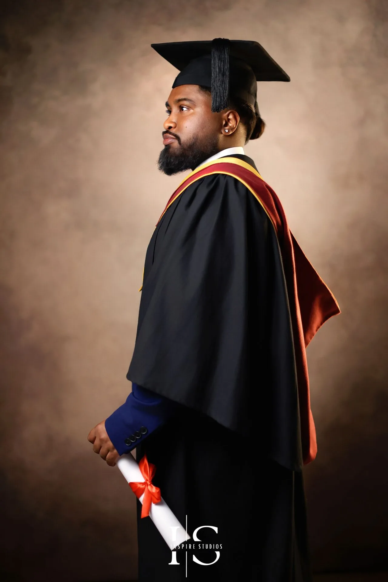Graduate posing in a vintage-style studio portrait photoshoot in London with elegant classic backdrop, formal graduation gown and timeless fine art lighting.