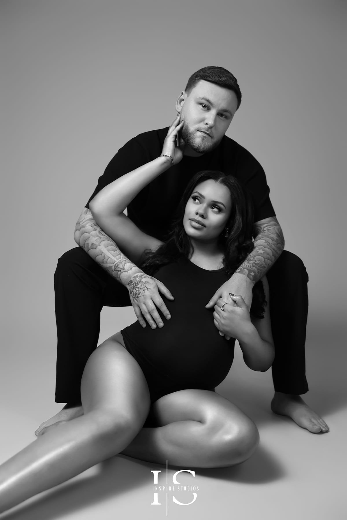 Maternity photoshoot with husband in London, featuring a romantic baby bump pose in studio.
