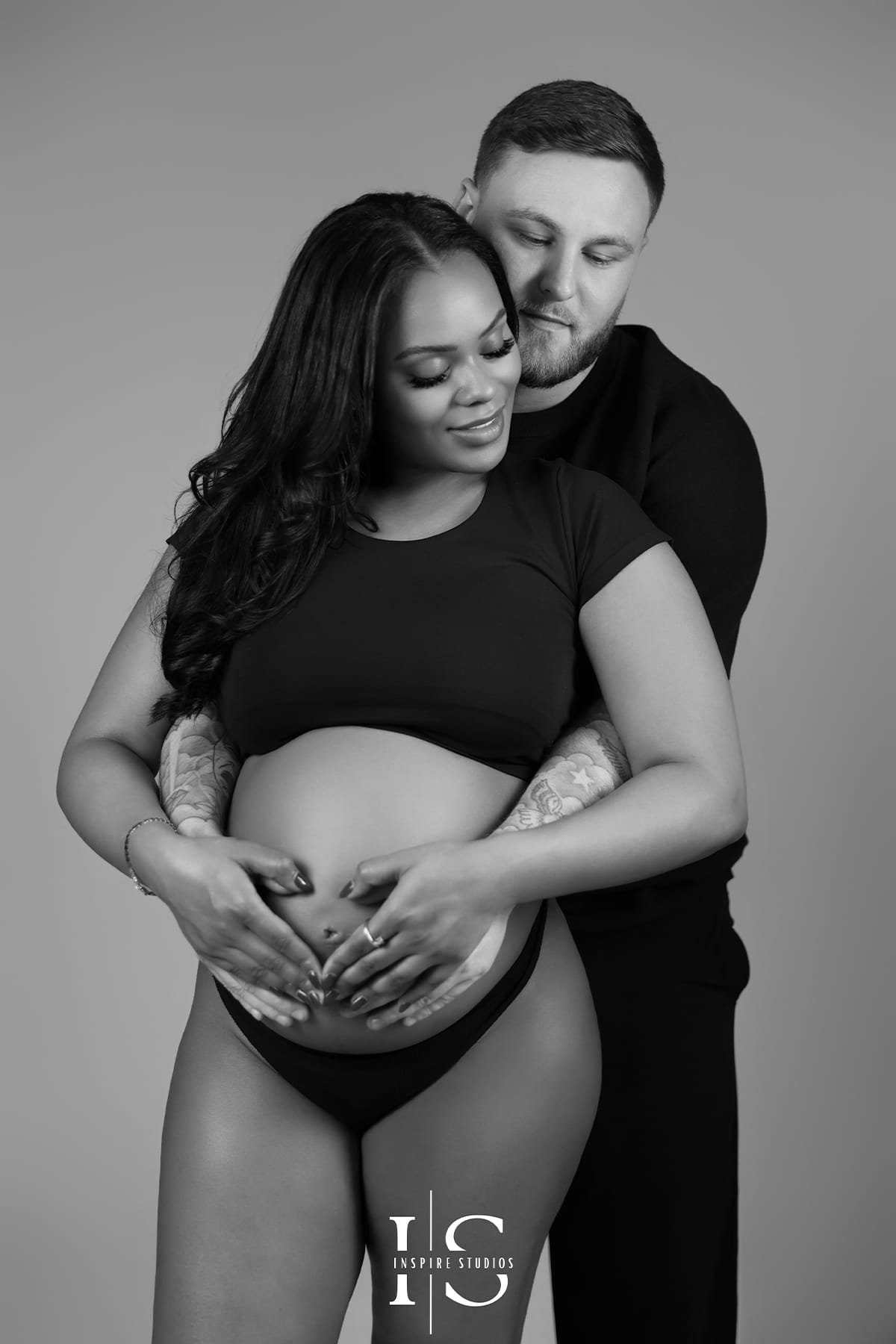 Pregnancy couple photoshoot in London with partner kissing the baby bump in a studio setting.