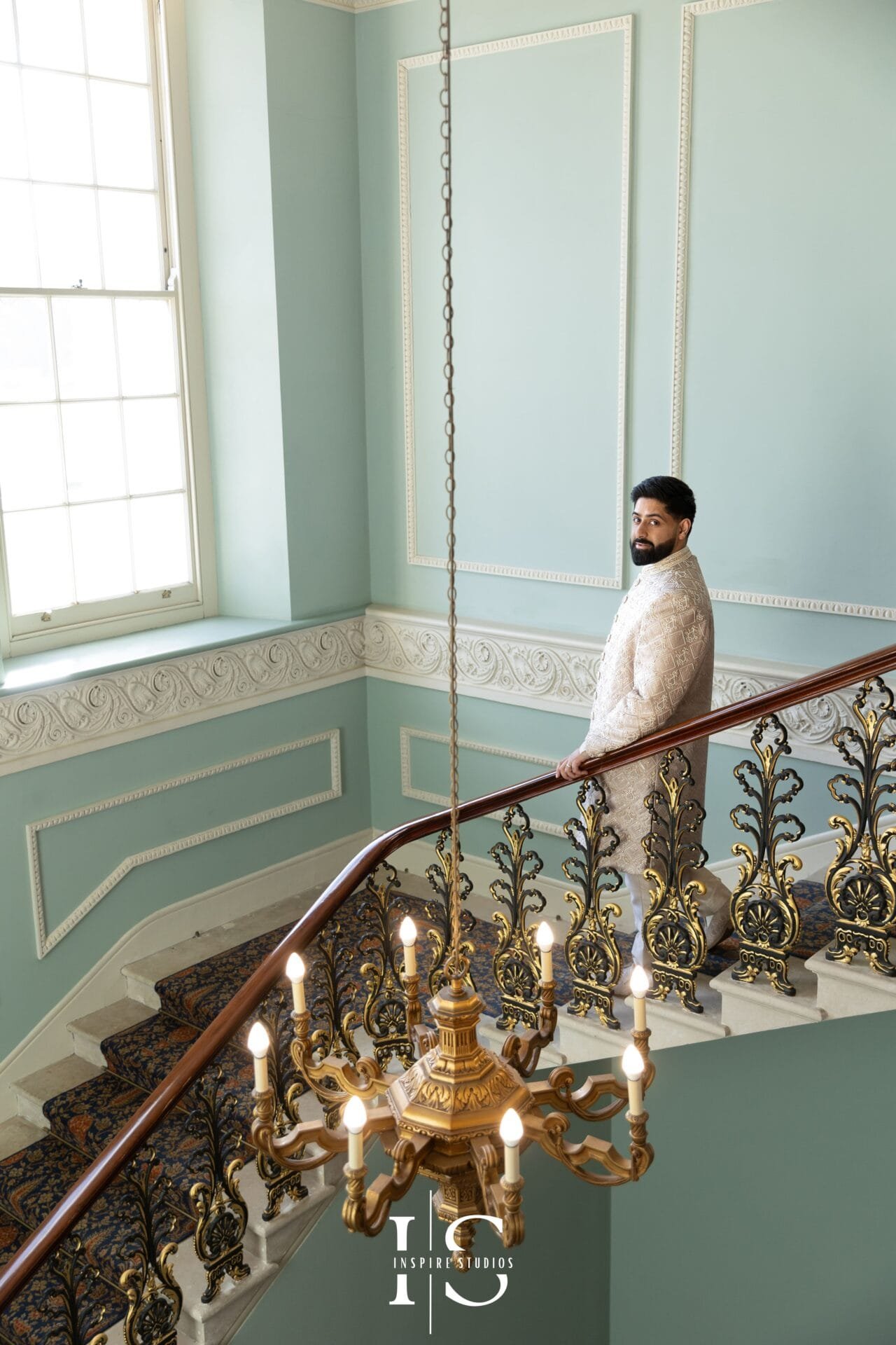 Groom in Pakistani wedding attire posing on the Hylands House Grand Staircase.