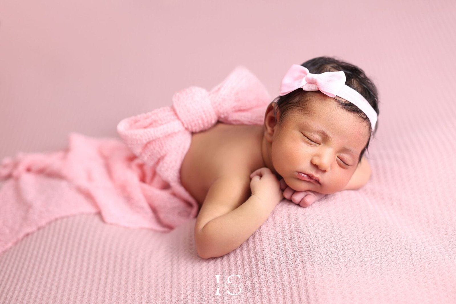 Newborn photoshoot for girls in London with a baby girl safely posed in a professional studio setup.