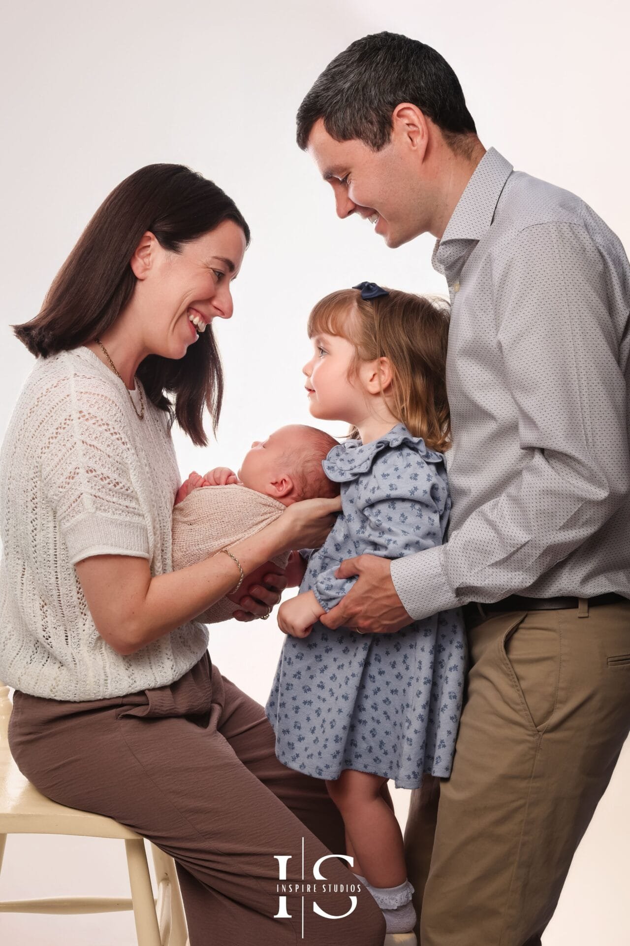 Newborn photoshoot with sister and parents in London, featuring a baby boy with his family in a studio portrait.