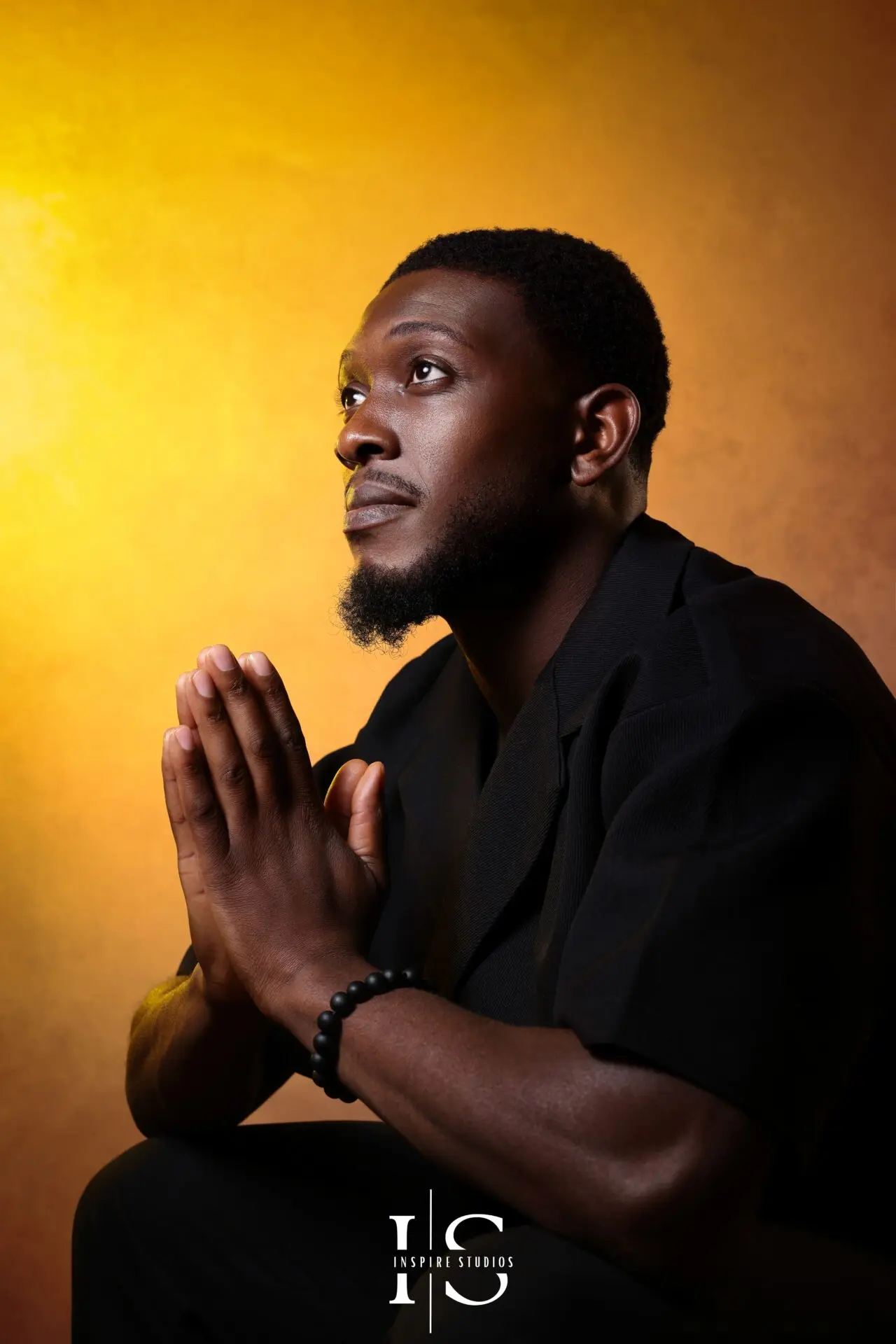 Man posing with his hands in prayer during a studio portrait photoshoot at Inspire Studios, London.