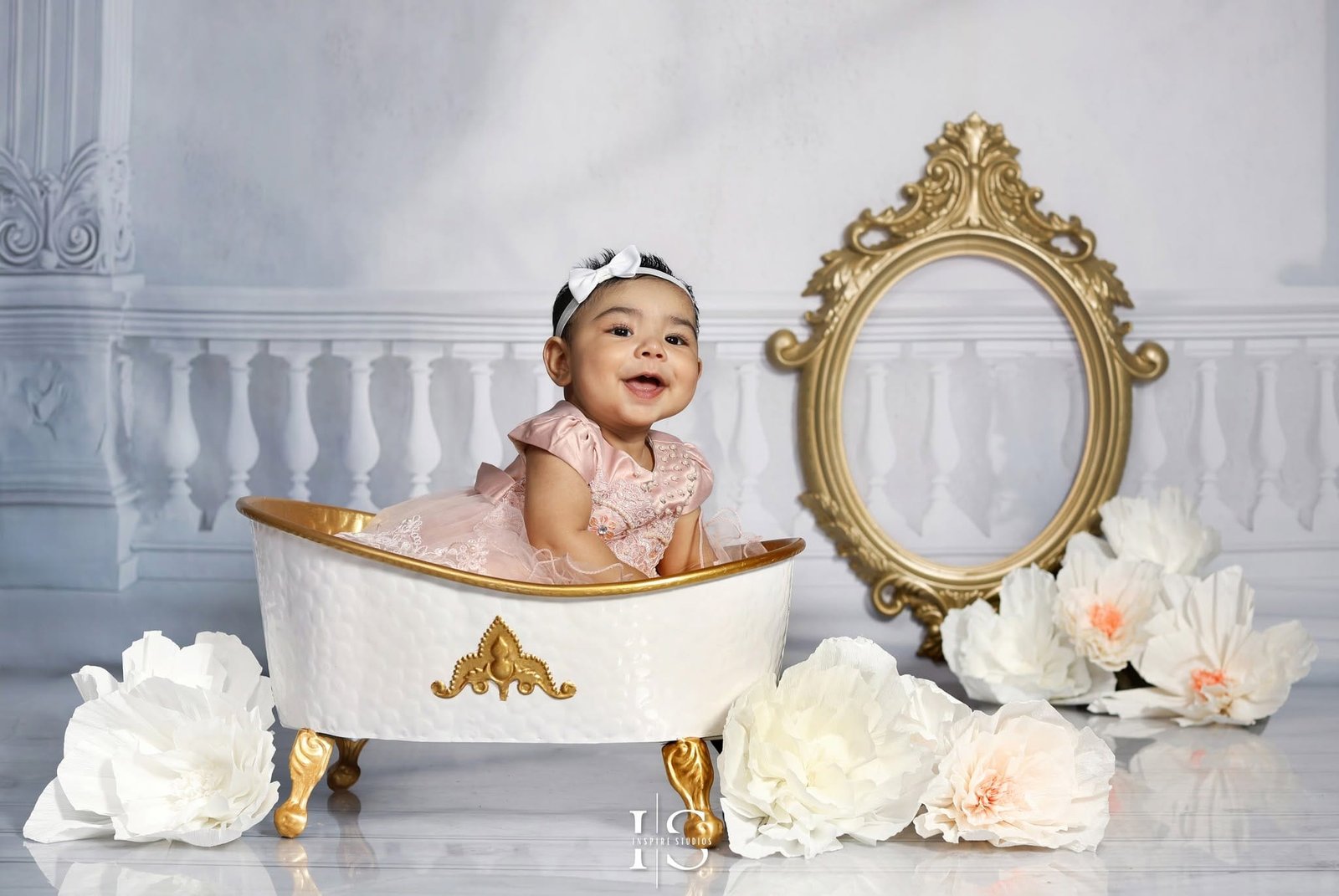 Six months baby photoshoot in London with baby girl in white and gold bathtub studio setup.